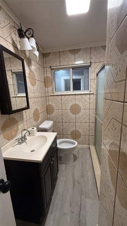 605 Biggs Terrace, Arlington, TX 76010 Bathroom featuring patterned wall tiling, a vanity with a dark wood-finish cabinet, a white sink, and light wood-finish flooring