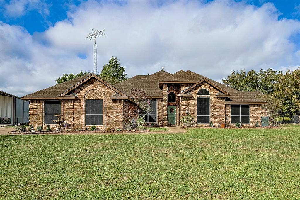 2042 County Road 1072, Greenville, TX 75401 Single-story brick exterior featuring a multi-gabled roofline, arched window detailing, and a covered entryway
