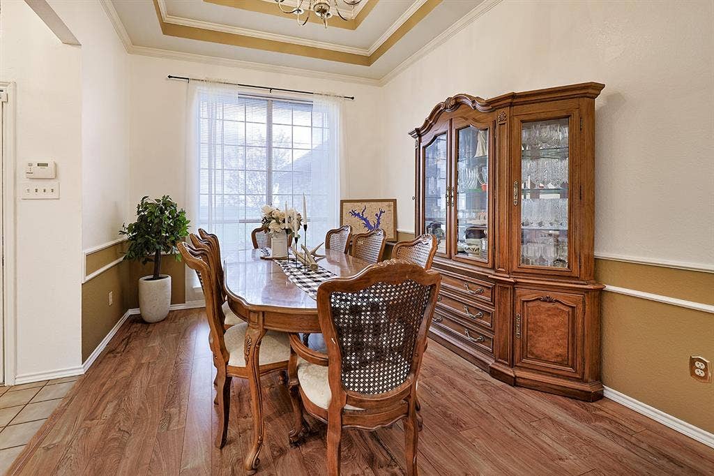 2042 County Road 1072, Greenville, TX 75401 Dining area featuring wood-finish flooring, tray ceiling, decorative wall molding, and a large window