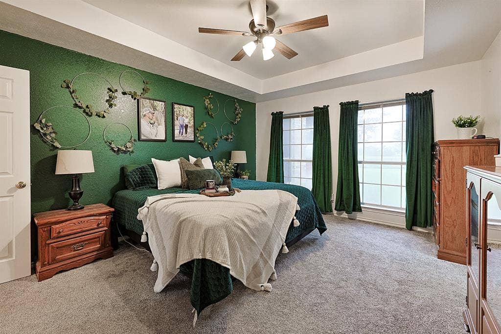 2042 County Road 1072, Greenville, TX 75401 Tray ceiling featuring a central multi-blade ceiling fan with integrated lighting and multi-pane windows