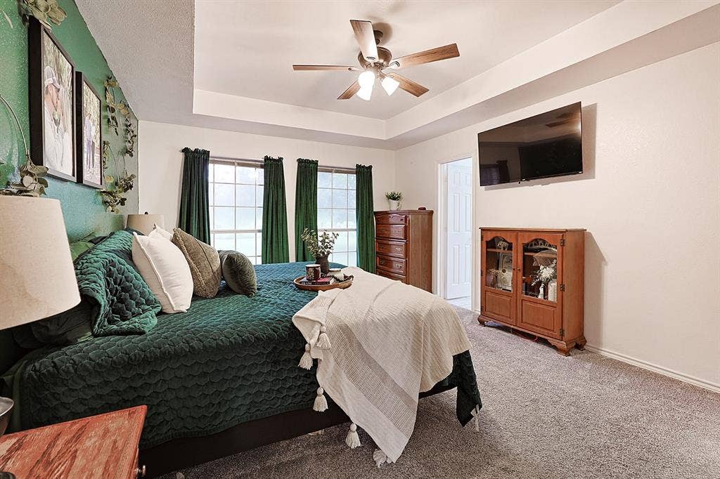 2042 County Road 1072, Greenville, TX 75401 Tray ceiling with central ceiling fan, grid-pattern windows, and neutral carpeting
