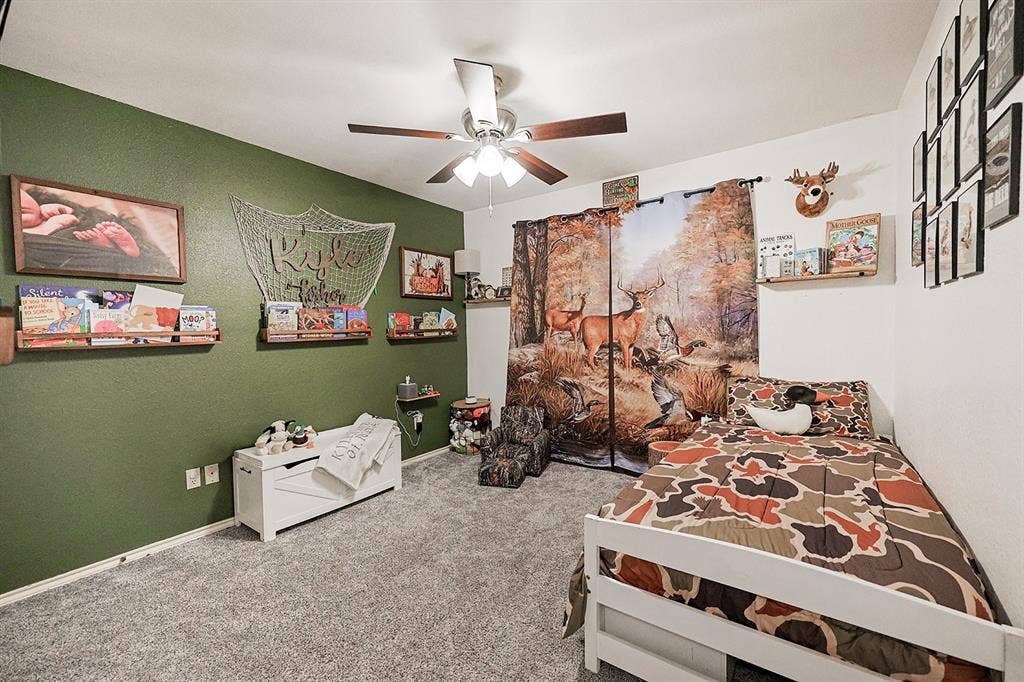 2042 County Road 1072, Greenville, TX 75401 Bedroom featuring wall-to-wall carpeting, ceiling fan with integrated lighting, and built-in wooden shelving