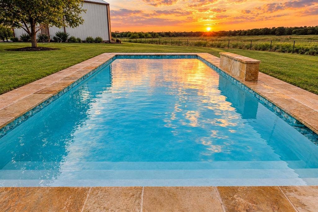 2042 County Road 1072, Greenville, TX 75401 In-ground rectangular swimming pool featuring stone-finish coping, a built-in water feature, integrated stairs, and expansive lawn area