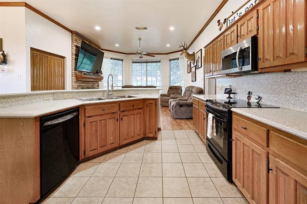 2042 County Road 1072, Greenville, TX 75401 Kitchen featuring wood cabinetry, stone-finish countertops, tile flooring, recessed lighting, and a brick fireplace
