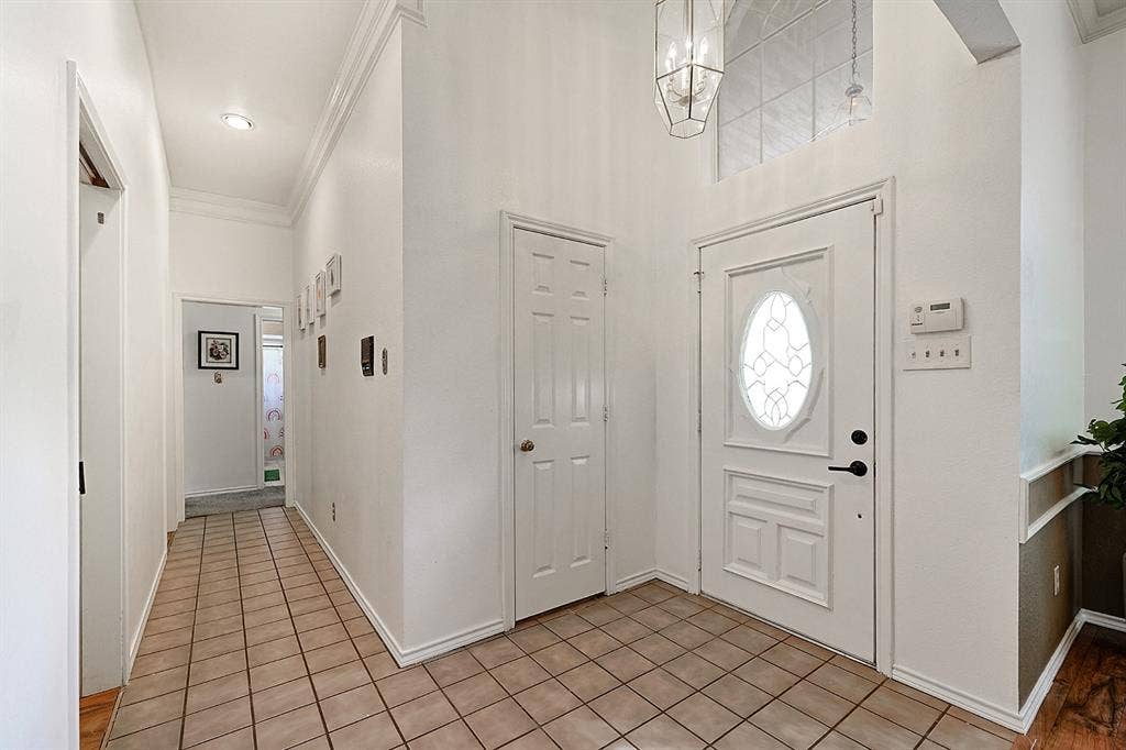 2042 County Road 1072, Greenville, TX 75401 Foyer featuring high ceilings, a transom window above an oval-glass entry door, ceramic tile flooring, and a multi-light geometric pendant fixture