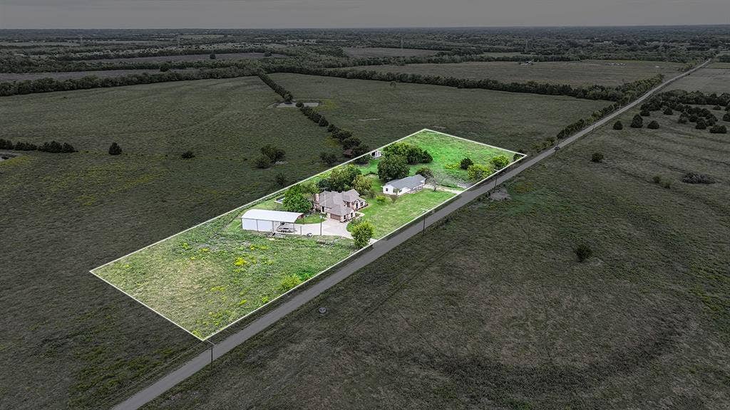 2042 County Road 1072, Greenville, TX 75401 Aerial perspective of property featuring two residences, a metal-roofed detached structure, paved driveway, and expansive acreage