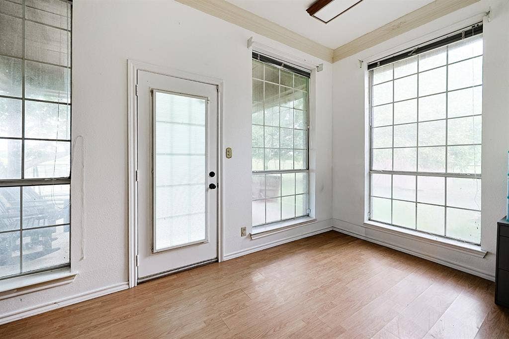 2042 County Road 1072, Greenville, TX 75401 Sun-filled room featuring wood-finish flooring, grid-patterned windows, crown molding, and a glass-paneled exterior door