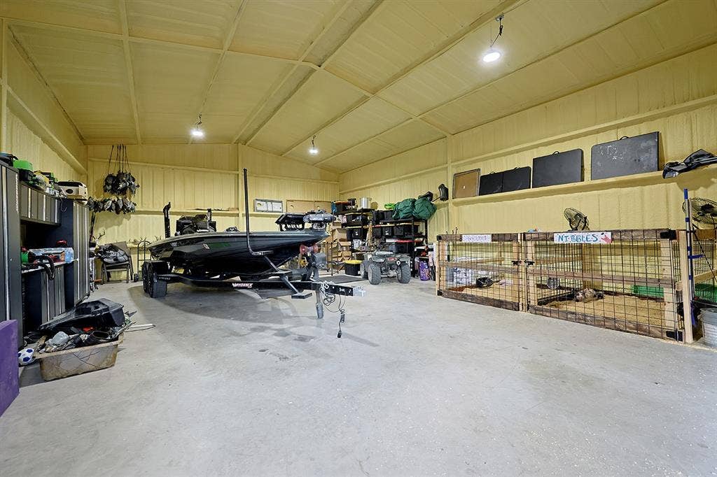 2042 County Road 1072, Greenville, TX 75401 Expansive metal workshop featuring high-clearance ceilings, concrete flooring, integrated overhead lighting, and built-in wall shelving