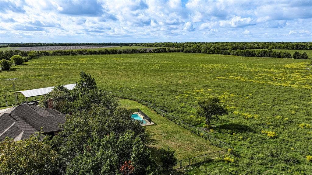 2042 County Road 1072, Greenville, TX 75401 Expansive acreage featuring a fenced swimming pool, metal-roofed carport, mature trees, and open meadowland