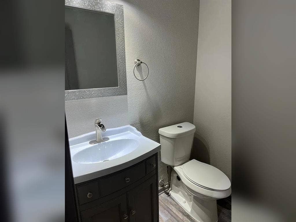 2500 Sierra Drive, McKinney, TX 75071 Vanity with under-sink storage, decorative mirror, modern single-handle faucet, and wood-finish flooring