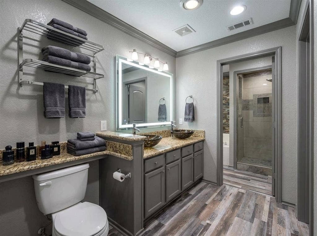 2500 Sierra Drive, McKinney, TX 75071 Dual vessel sinks, granite-look countertops, wood-finish flooring, built-in shelving, and a separate glass-enclosed shower