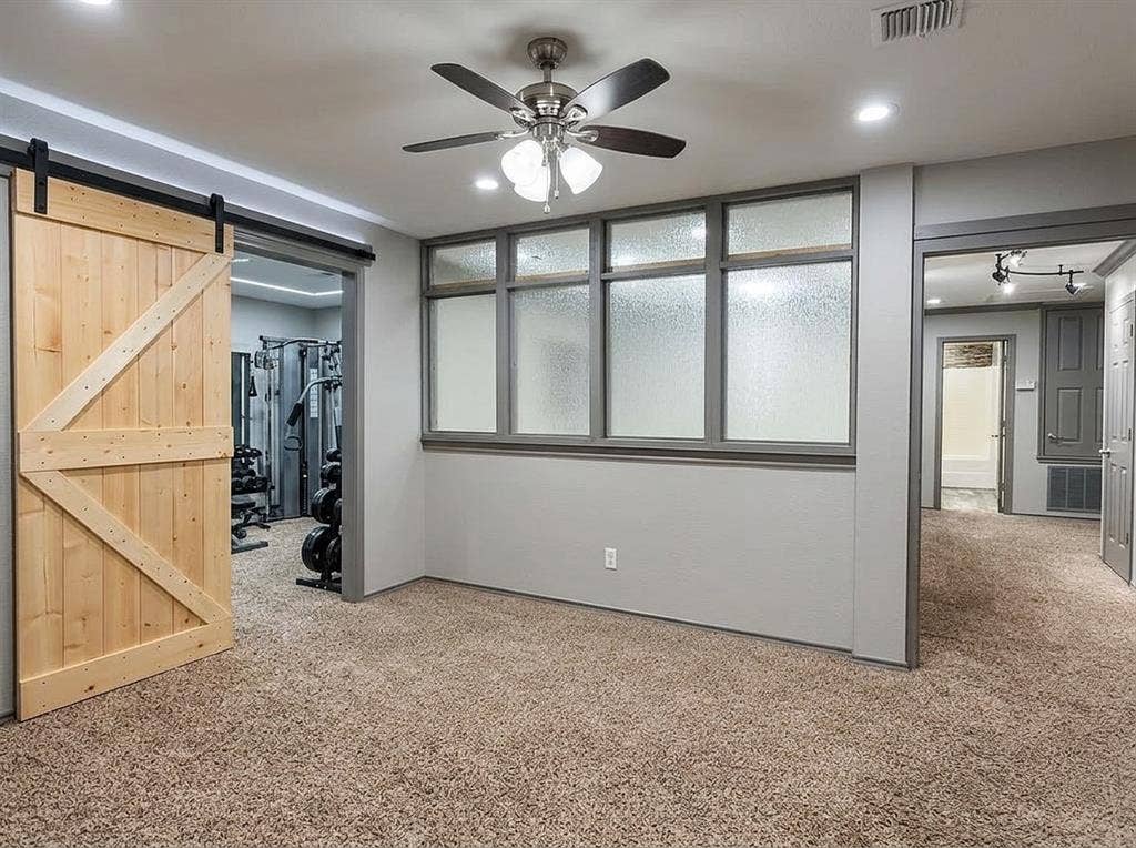 2500 Sierra Drive, McKinney, TX 75071 Carpeted room with a sliding barn door, ceiling fan with integrated lighting, recessed lighting, and a multi-pane window with textured glass