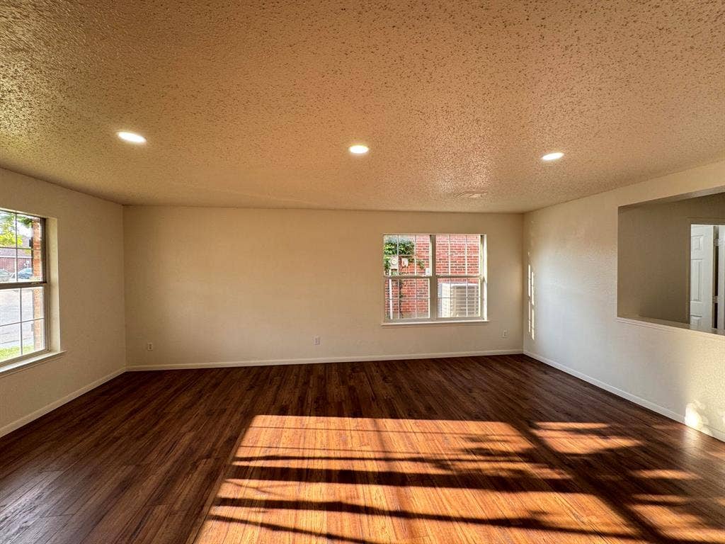 Spacious interior room featuring wood-finish flooring, recessed lighting, and multiple windows
