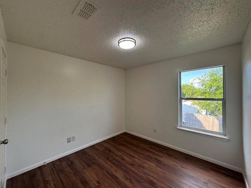 Room featuring wood-finish flooring, white baseboards, and a single window with a white sill