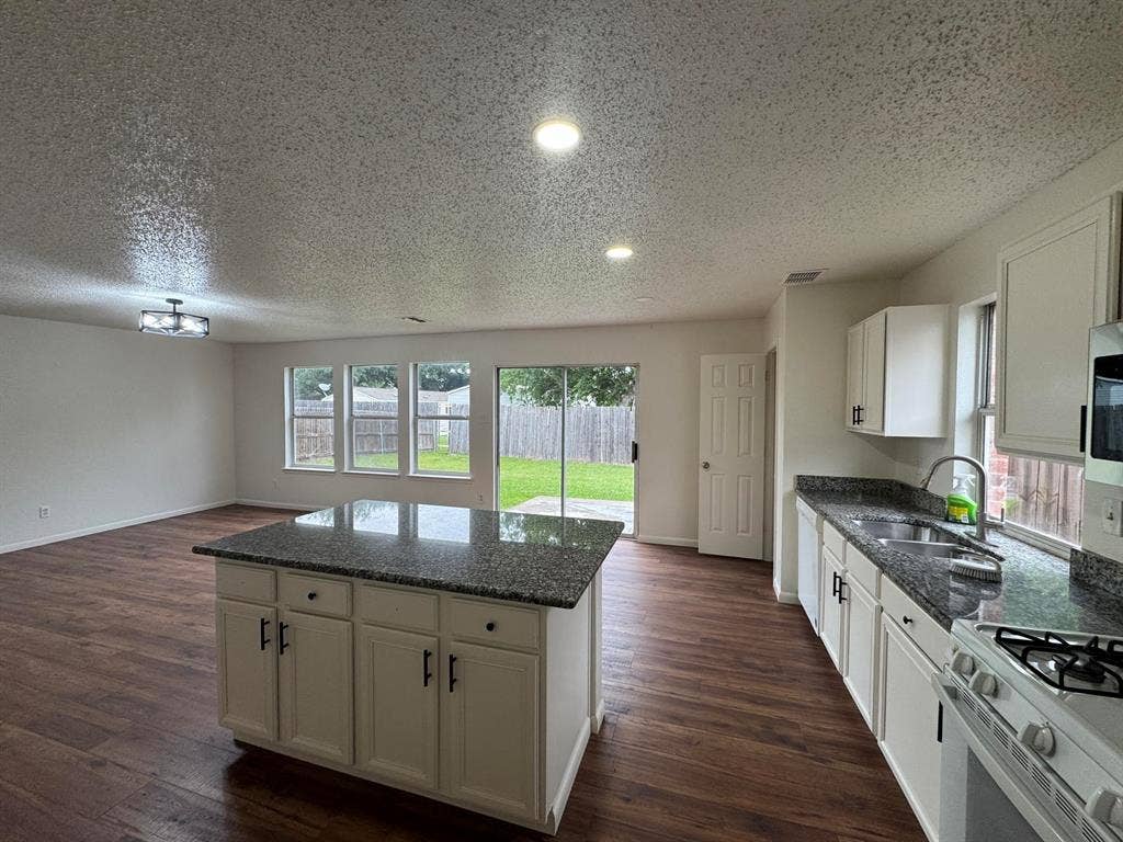7305 Marsland Lane, Arlington, TX 76001 Open-concept kitchen and living area featuring wood-finish flooring, recessed lighting, and a kitchen island with stone countertops