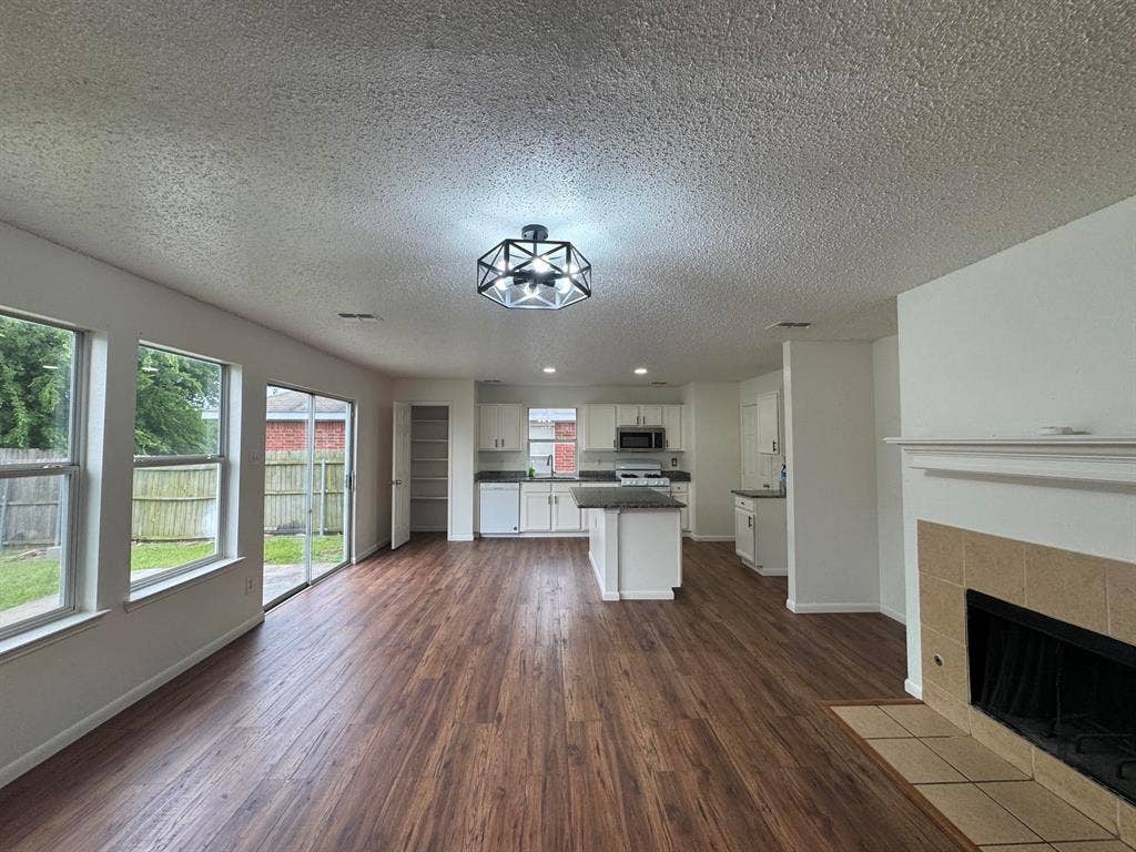 7305 Marsland Lane, Arlington, TX 76001 Open-concept living area featuring wood-finish flooring, a tiled fireplace, and a modern geometric ceiling light fixture