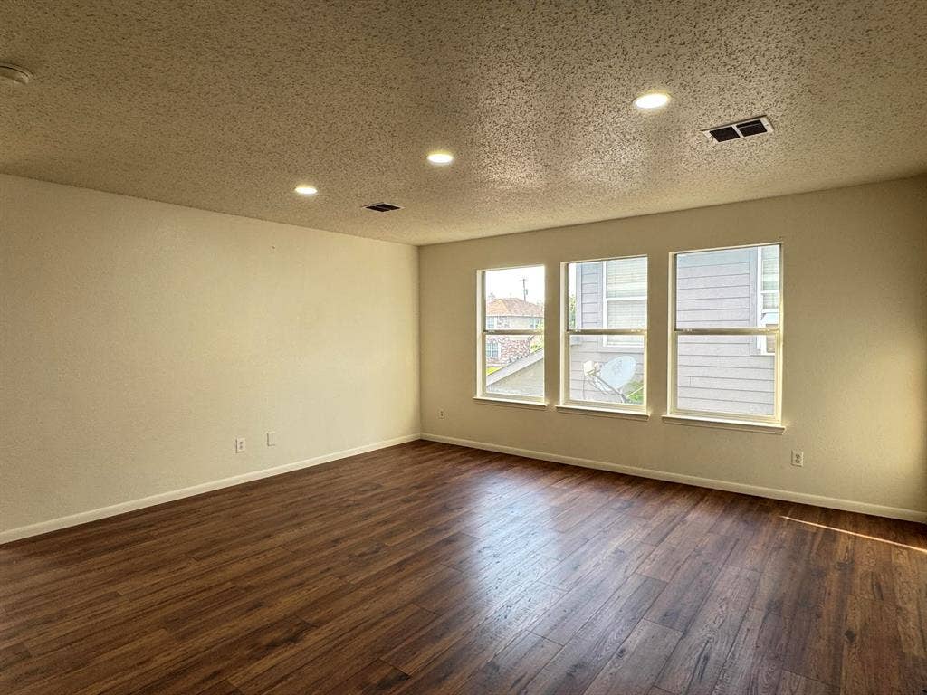 7305 Marsland Lane, Arlington, TX 76001 Spacious room featuring wood-finish flooring, recessed ceiling lighting, three windows, and light-colored walls