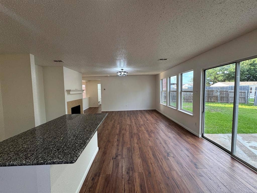 7305 Marsland Lane, Arlington, TX 76001 Spacious interior featuring wood-finish flooring, a contemporary ceiling light fixture, and a breakfast bar with a speckled countertop