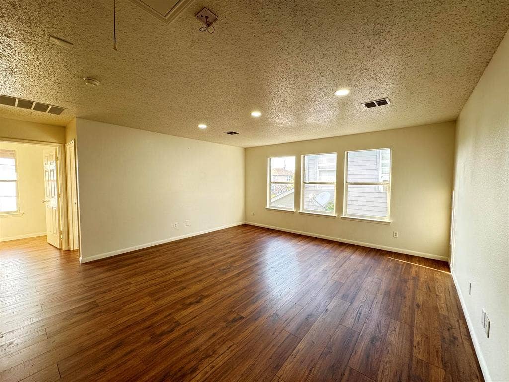 7305 Marsland Lane, Arlington, TX 76001 Spacious room featuring wood-finish flooring, recessed lighting, and three large windows