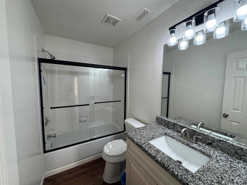 7305 Marsland Lane, Arlington, TX 76001 Bathroom featuring a tub/shower combination with black-framed sliding glass doors and white subway tile surround