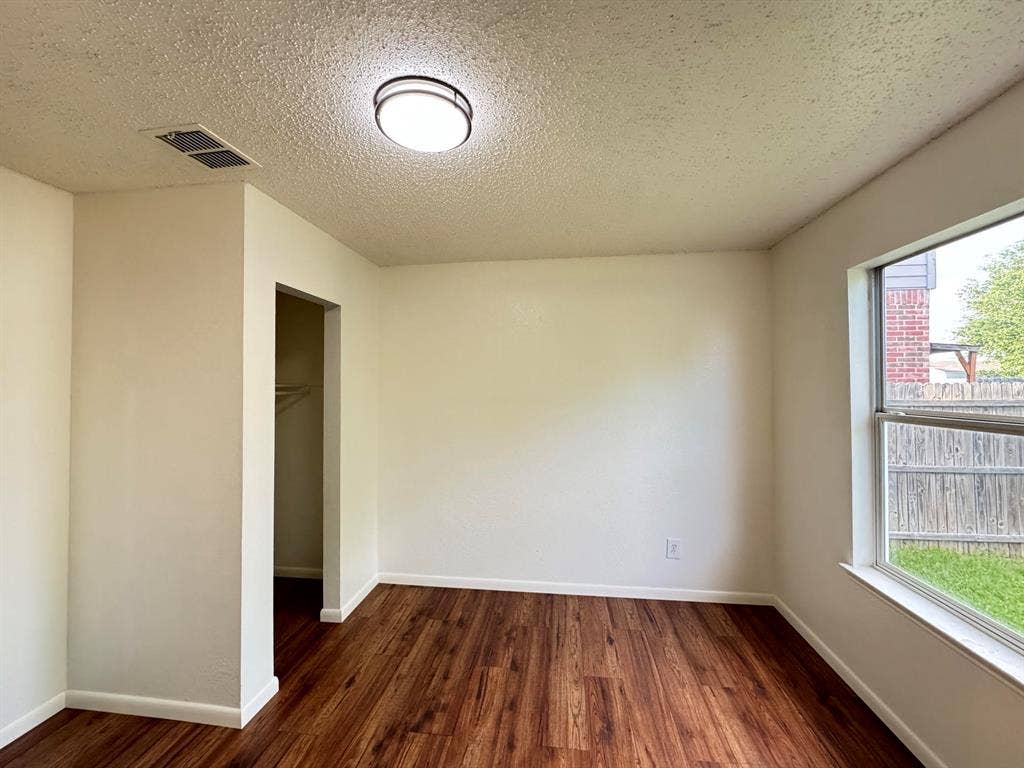 7305 Marsland Lane, Arlington, TX 76001 Spacious interior room featuring wood-finish flooring, white baseboards, and a window with a backyard outlook
