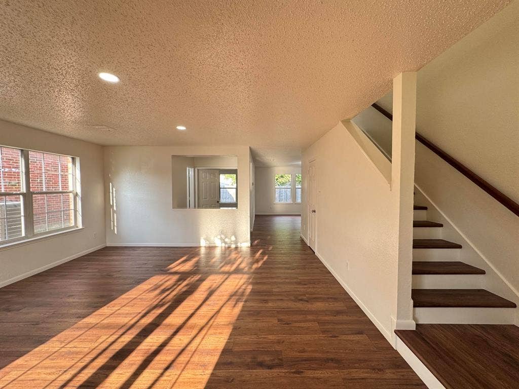 7305 Marsland Lane, Arlington, TX 76001 Open-concept living area featuring wood-finish flooring, recessed lighting, and a prominent staircase with wood treads and handrail