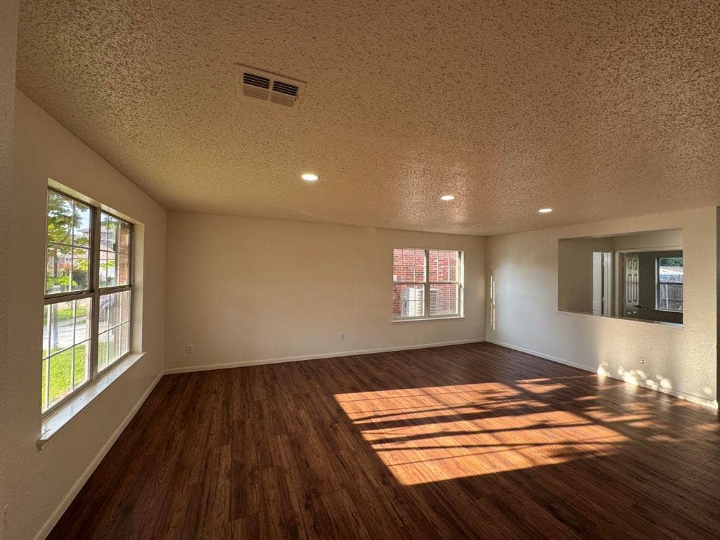 7305 Marsland Lane, Arlington, TX 76001 Spacious interior room featuring wood-finish flooring, two large windows, and a pass-through opening