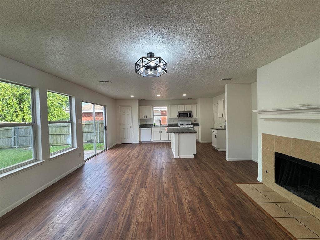7305 Marsland Lane, Arlington, TX 76001 Spacious open-concept living area featuring wood-finish flooring, a contemporary ceiling light fixture, and large windows