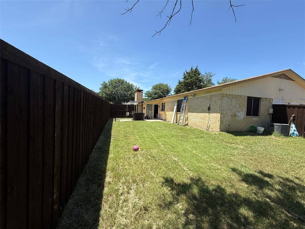 2809 Royalty Drive, Garland, TX 75044 Expansive backyard with a manicured lawn, full-height privacy fencing, and a brick exterior