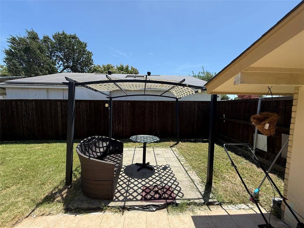 2809 Royalty Drive, Garland, TX 75044 Backyard featuring a paved patio area, green lawn, wood fence, and a structured canopy