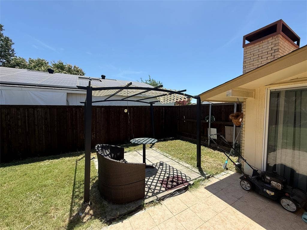 2809 Royalty Drive, Garland, TX 75044 Private backyard with wood fencing, a brick chimney, and an attached covered patio