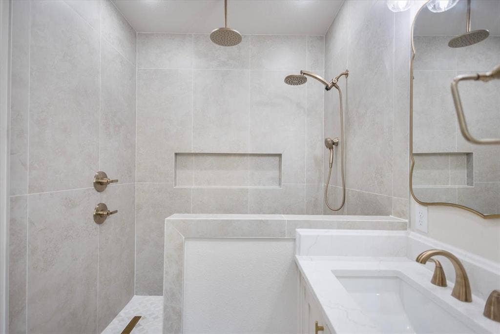 Walk-in shower with light-toned wall tile, built-in shower bench, and recessed shower niches