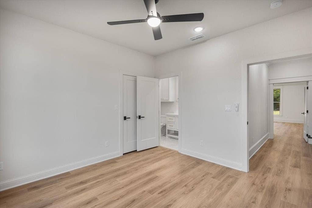 Wood-finish flooring, white walls, and a contemporary ceiling fan with integrated lighting