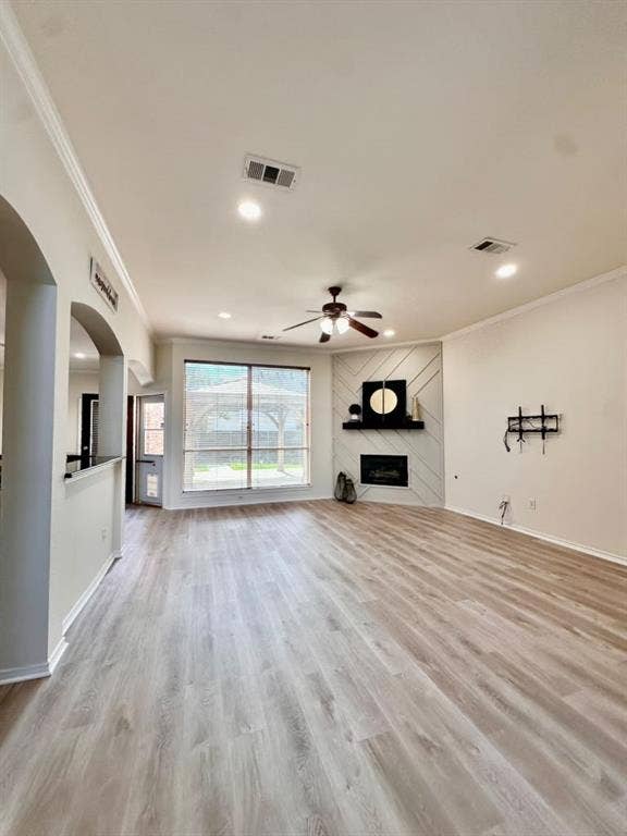 Living area featuring wood-finish flooring, recessed lighting, ceiling fan, and corner fireplace with decorative wall paneling and a floating mantel