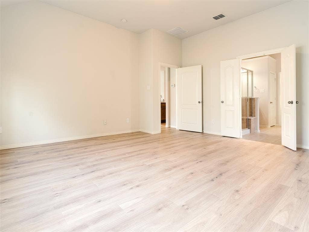 Room featuring wood-finish flooring, vaulted ceiling, and dual-panel interior doors
