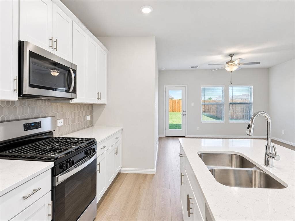 5204 Golden Trout Drive, Princeton, TX 75071 Kitchen featuring white cabinetry, stainless steel appliances, a double basin sink, and light-toned wood-finish flooring