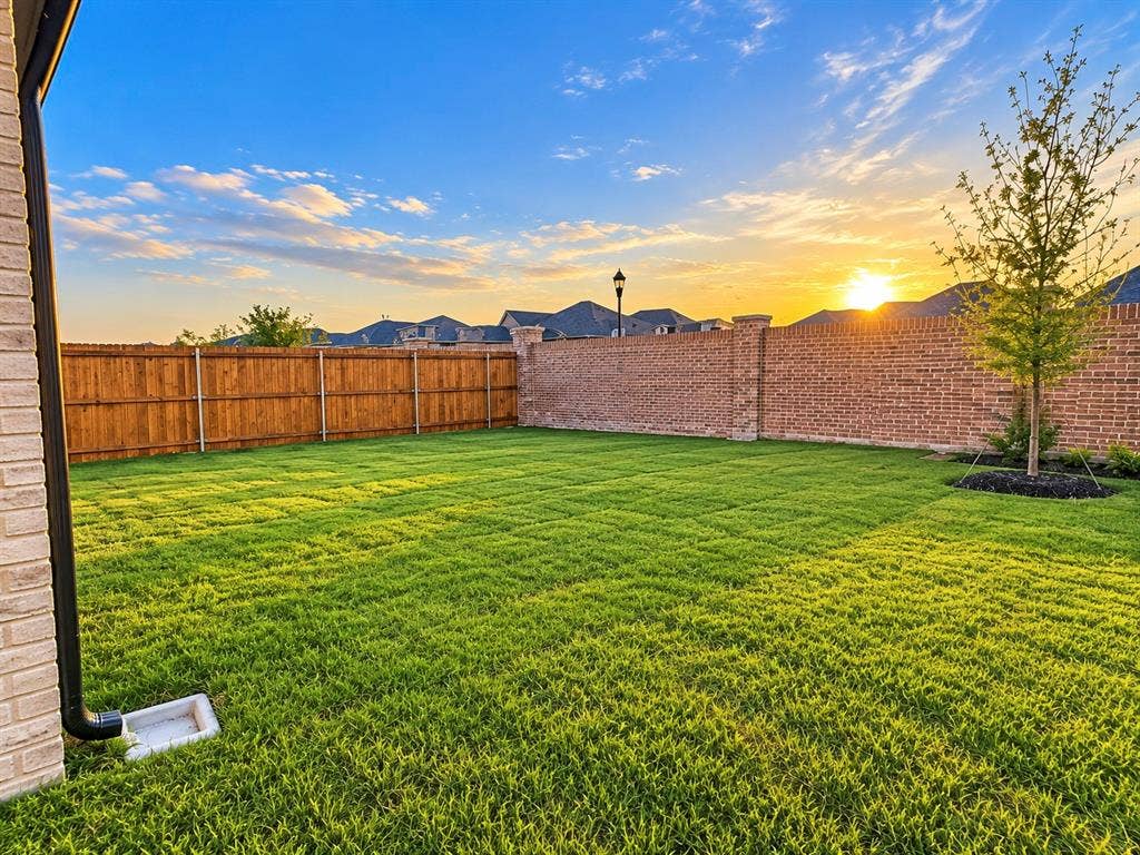 5204 Golden Trout Drive, Princeton, TX 75071 Expansive rear yard featuring green lawn, brick perimeter wall, and wood fencing
