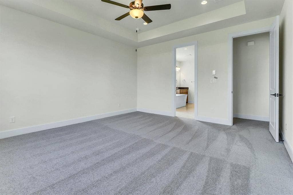 115 Cottonwood Court, Murphy, TX 75094 Spacious room featuring gray carpeting, tray ceiling, recessed lighting, and a ceiling fan with integrated light