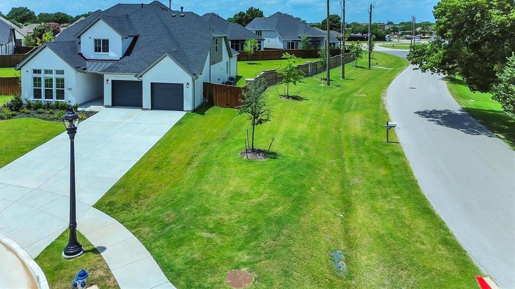 115 Cottonwood Court, Murphy, TX 75094 Contemporary architecture featuring a two-car garage, dormer window, extensive concrete driveway, and front landscaping