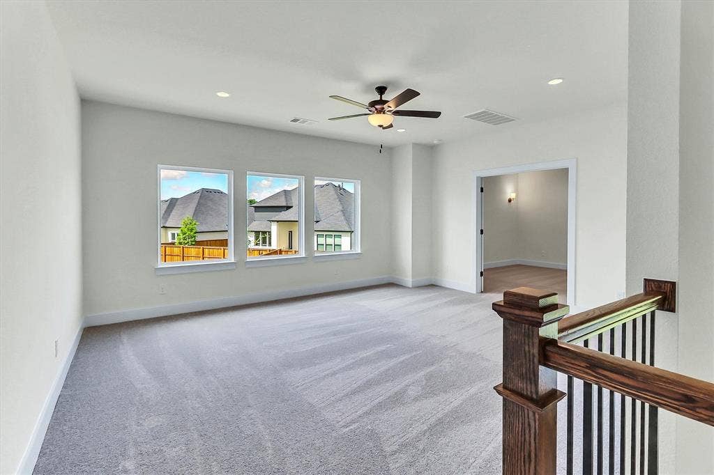 115 Cottonwood Court, Murphy, TX 75094 Light grey carpeting with recessed lighting, a ceiling fan, and three large windows