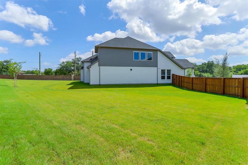 115 Cottonwood Court, Murphy, TX 75094 Expansive green lawn, dark shingle roofing, horizontal siding, white exterior walls, and a wood privacy fence