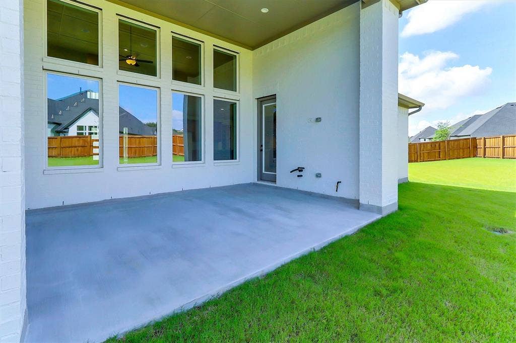 115 Cottonwood Court, Murphy, TX 75094 Expansive concrete patio with a full-light glass door, large transom windows, and a manicured lawn