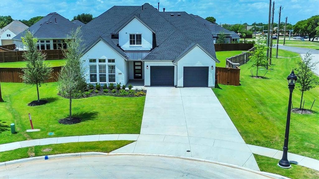 115 Cottonwood Court, Murphy, TX 75094 Contemporary white exterior with dark gray roof, two-car garage, manicured lawn with mature trees, and a concrete driveway