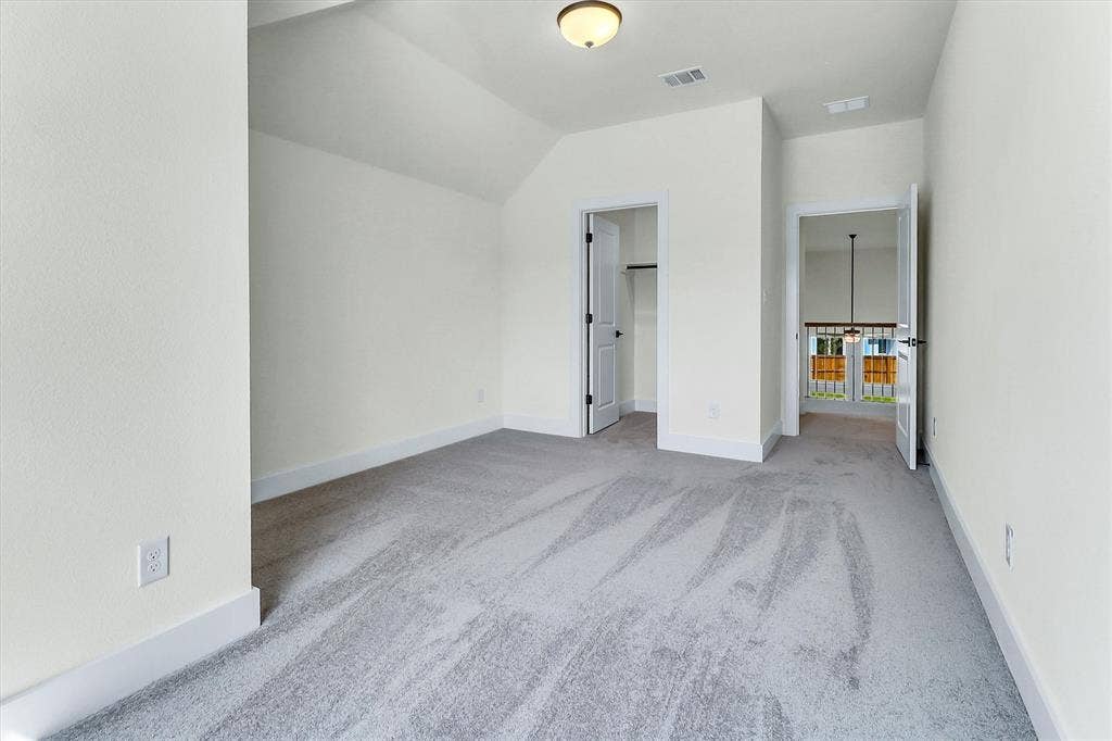 115 Cottonwood Court, Murphy, TX 75094 Carpeted room featuring a sloped ceiling, overhead lighting, and white trim