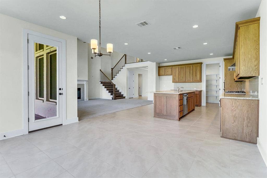 115 Cottonwood Court, Murphy, TX 75094 Light-toned tile flooring, recessed lighting, wood-finish cabinetry, built-in shelving, and a prominent staircase with dark wood-finish treads