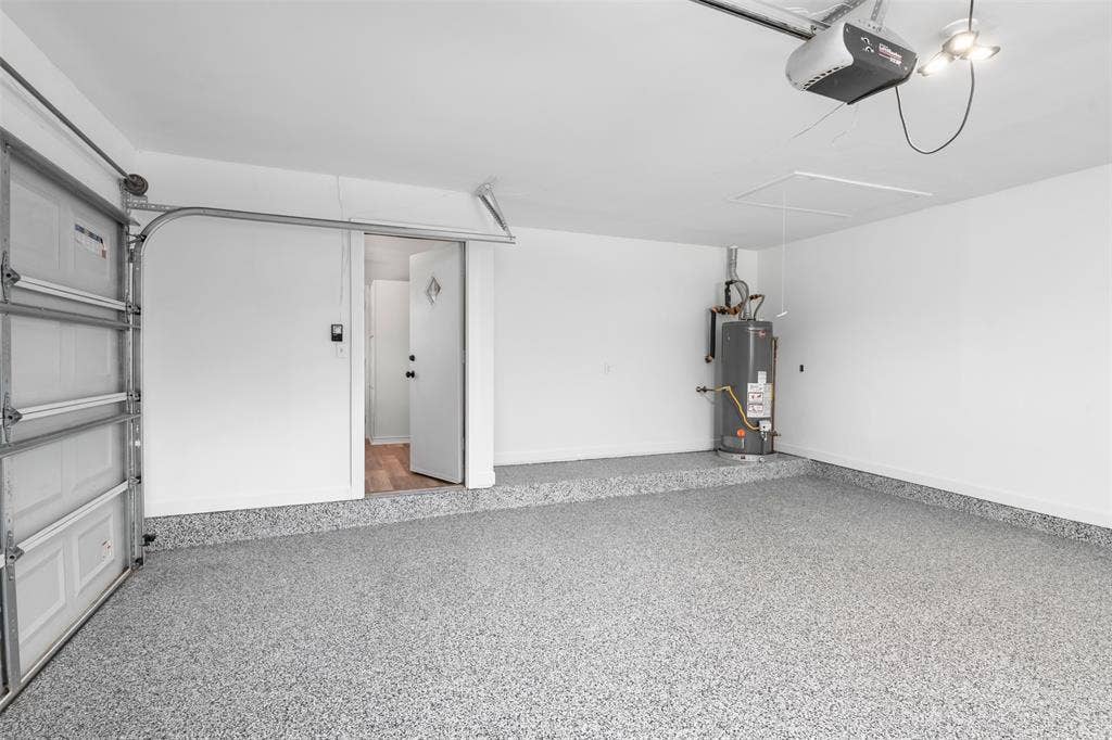Garage featuring a speckled epoxy floor, white painted walls, and a finished ceiling with overhead lighting
