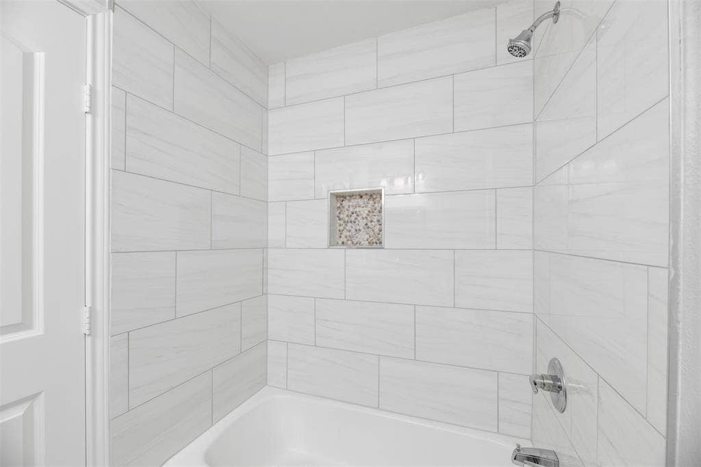 White subway tile shower surround with a built-in niche featuring mosaic tile