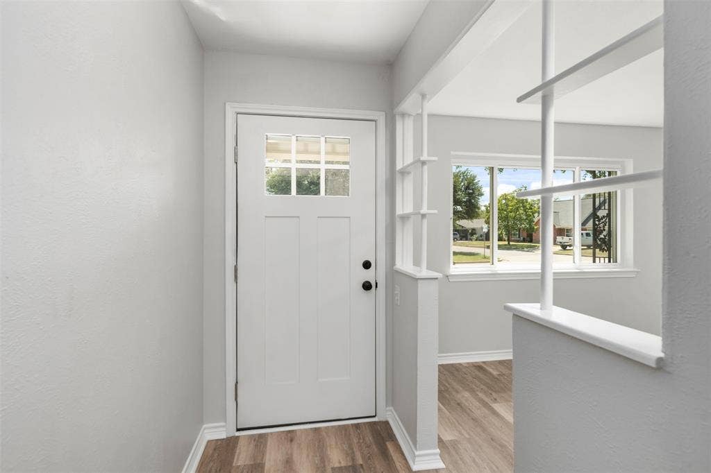 Entryway featuring a panel door with lites, wood-finish flooring, and decorative room divider
