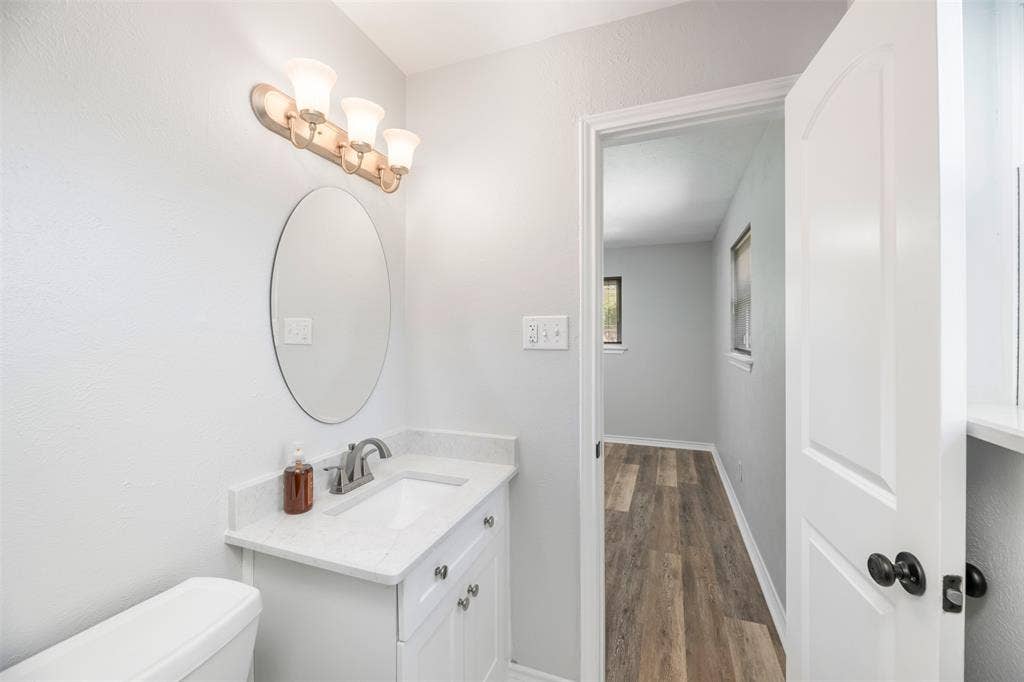 Vanity with a white countertop and integrated sink, brushed nickel faucet, and an oval mirror