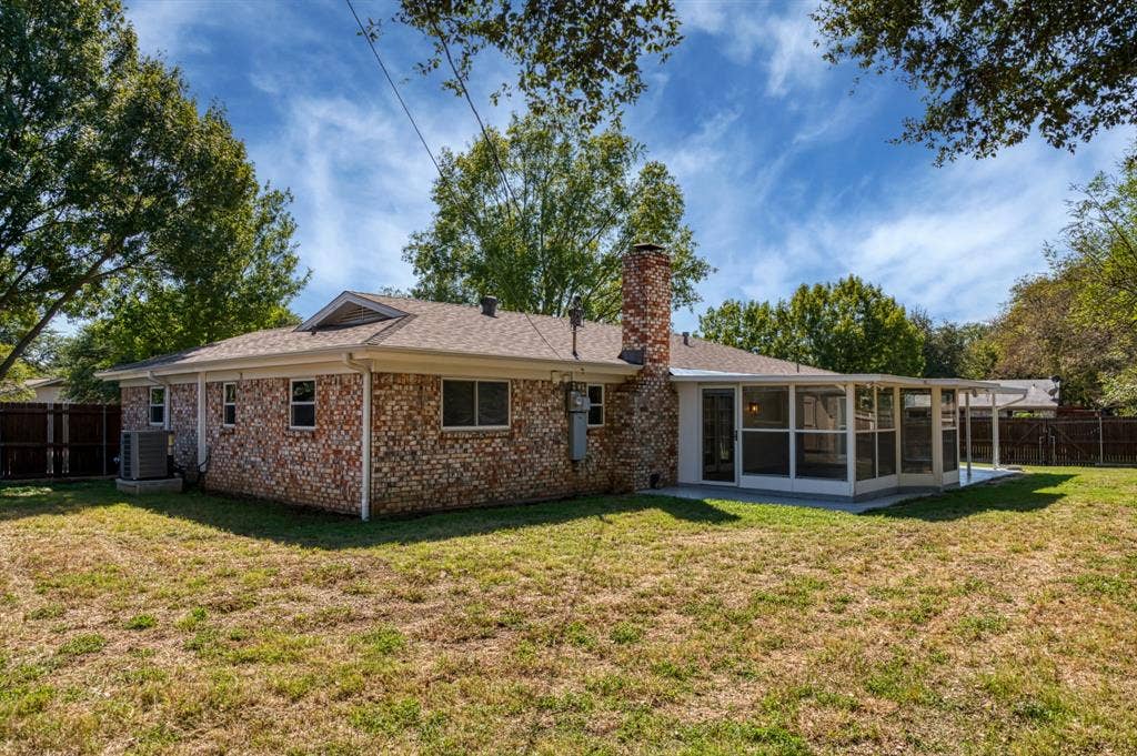 Brick exterior, screened enclosure, covered patio, exterior chimney, and a fenced perimeter